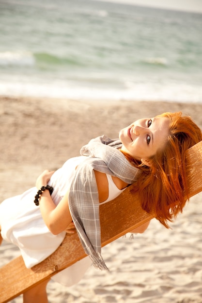 Foto muchacha pelirroja joven en la madera cerca del mar.