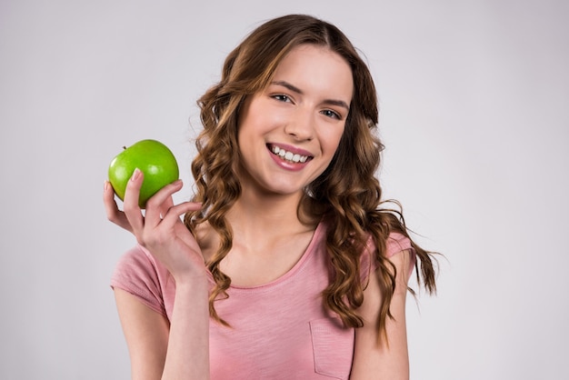 Muchacha que celebra la sonrisa verde de la manzana aislada.