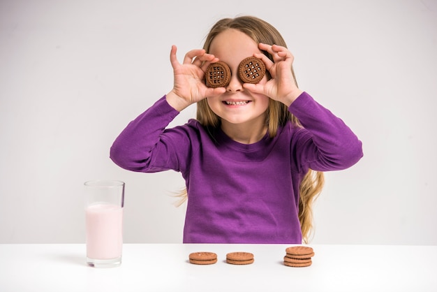 Muchacha que sostiene la galleta mientras que se sienta en la tabla.