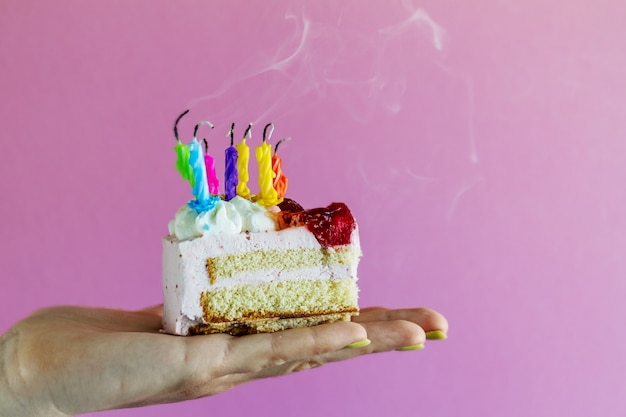 Muchacha que sostiene la torta de cumpleaños apetitosa hermosa con muchas velas sopladas. De cerca.