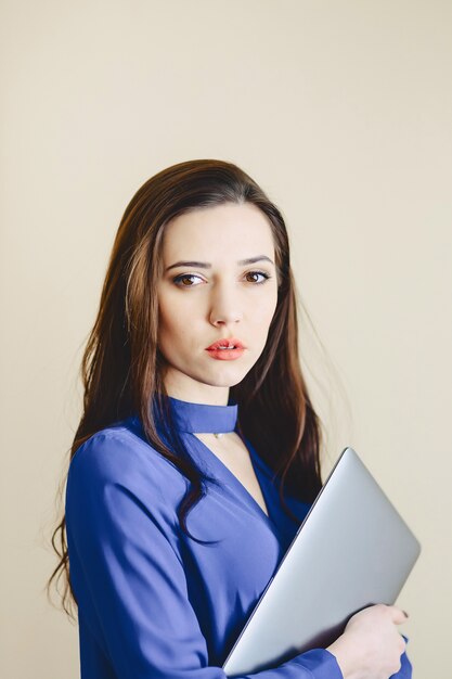 Muchacha del retrato con la computadora portátil en el fondo de la pared