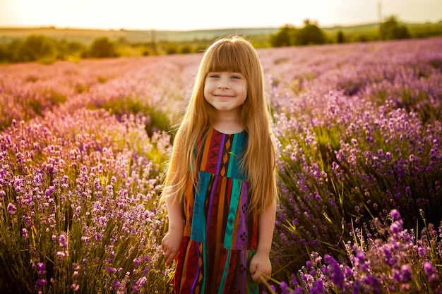 Muchacha de risa del niño en un campo de la lavanda en la puesta del sol.