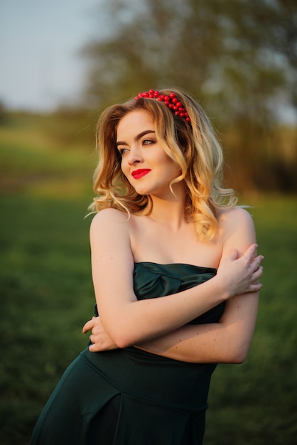 Muchacha rubia elegante de Yong en el vestido verde en el jardín en primavera.