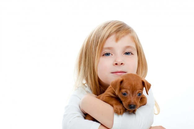 Muchacha rubia de los niños con el perrito mini pinscher del perro