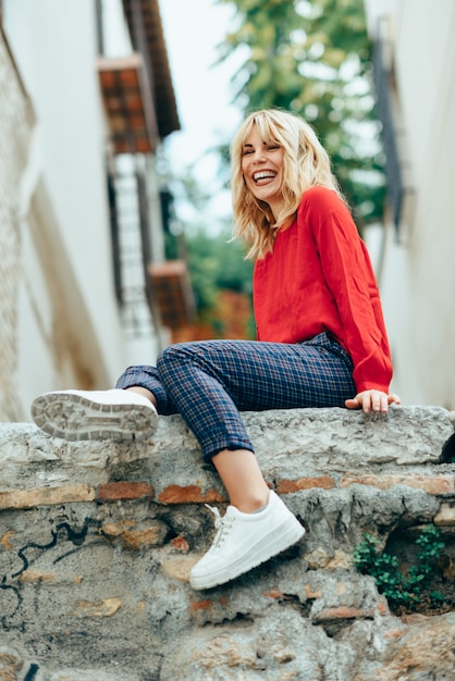 Muchacha rubia sonriente con la camisa roja que disfruta de vida al aire libre.