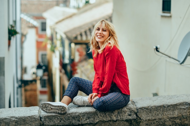 Muchacha rubia sonriente con la camisa roja que disfruta de vida al aire libre.