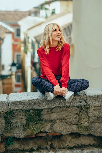 Muchacha rubia sonriente con la camisa roja que disfruta de vida al aire libre.