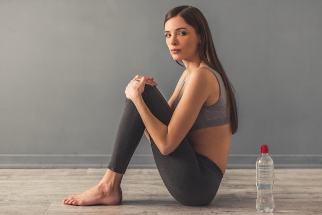 Foto la muchacha está sentada sola en el suelo, un agua detrás de ella.