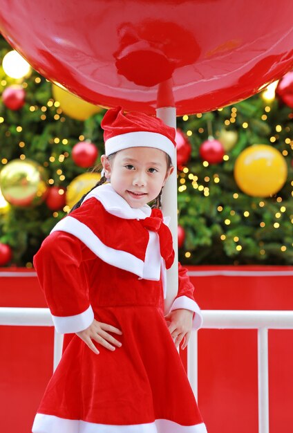 Muchacha sonriente del niño en el traje de Papá Noel con el fondo de la Navidad.