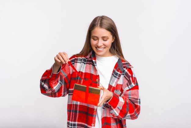 La muchacha sonriente rubia emocionada está desenvolviendo el regalo que recibió.