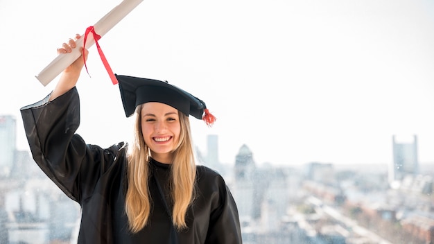 Muchacha sonriente de la vista delantera que se gradúa mirando la cámara