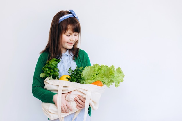 La muchacha sostiene la bolsa ecológica de compras con verduras, verduras sin plástico con fondo. Cero desperdicio, sin plástico Concepto ecológico.