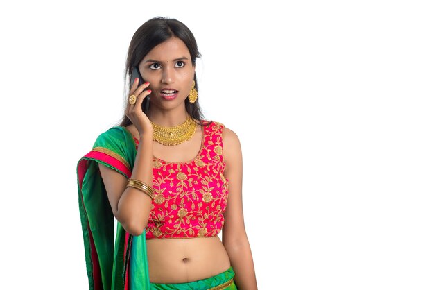 Muchacha tradicional india joven que usa un teléfono móvil o un smartphone aislado