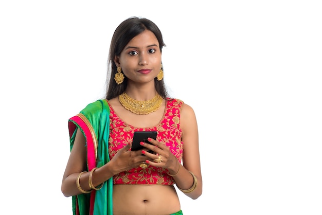 Muchacha tradicional india joven que usa un teléfono móvil o un smartphone aislado