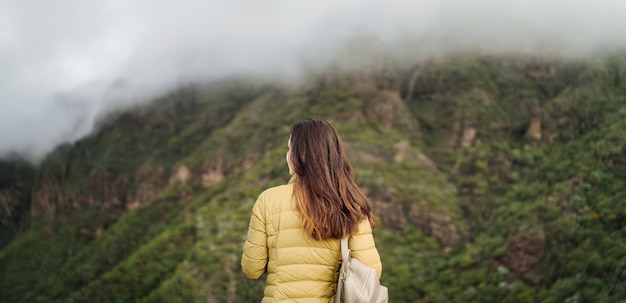 Muchacha triguena turística bonita que se relaja cerca de las montañas.