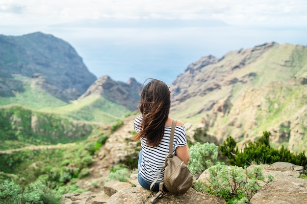 Muchacha triguena turística bonita que se relaja cerca de las montañas.