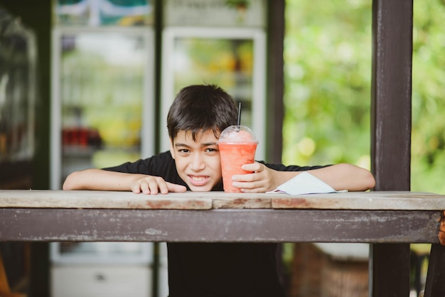 Muchacho adolescente bebiendo jugo de frutas en el parque camping horario de verano