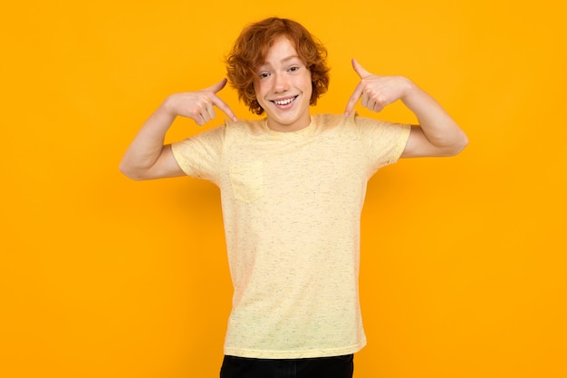 El muchacho adolescente en una camiseta con un diseño muestra una inscripción publicitaria en amarillo con espacio de copia