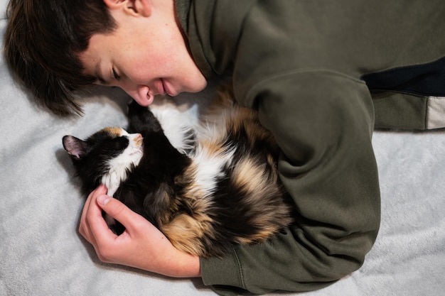 Muchacho adolescente con gatito acostado en el sofá El amor de los niños por las mascotas