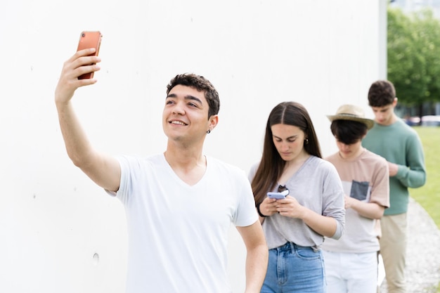 Muchacho adolescente hispano tomando un selfie en una cola