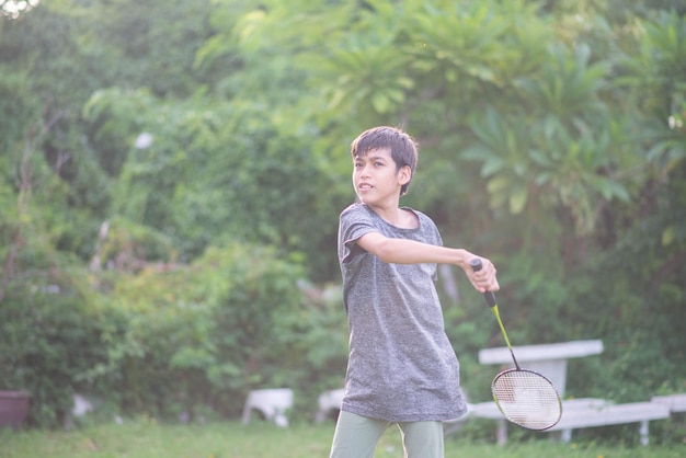 Foto muchacho adolescente jugando bádminton al aire libre parque al aire libre