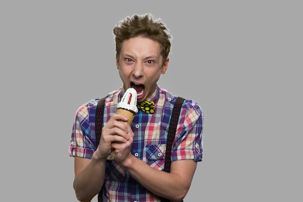 Muchacho adolescente loco comiendo helado. Muchacho adolescente divertido con helado mirando a cámara. Espacio para texto.