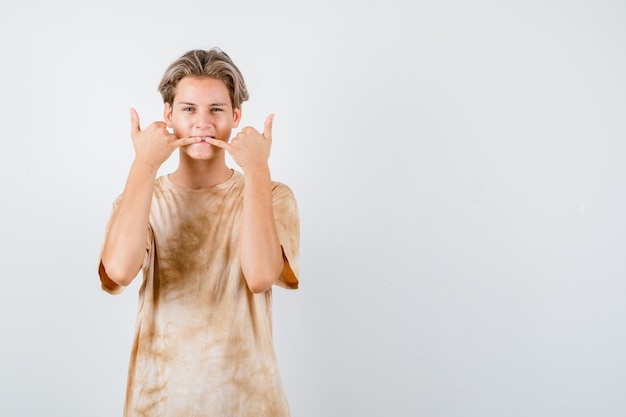 Muchacho adolescente silbando con los dedos en la camiseta y luciendo fresco, vista frontal.