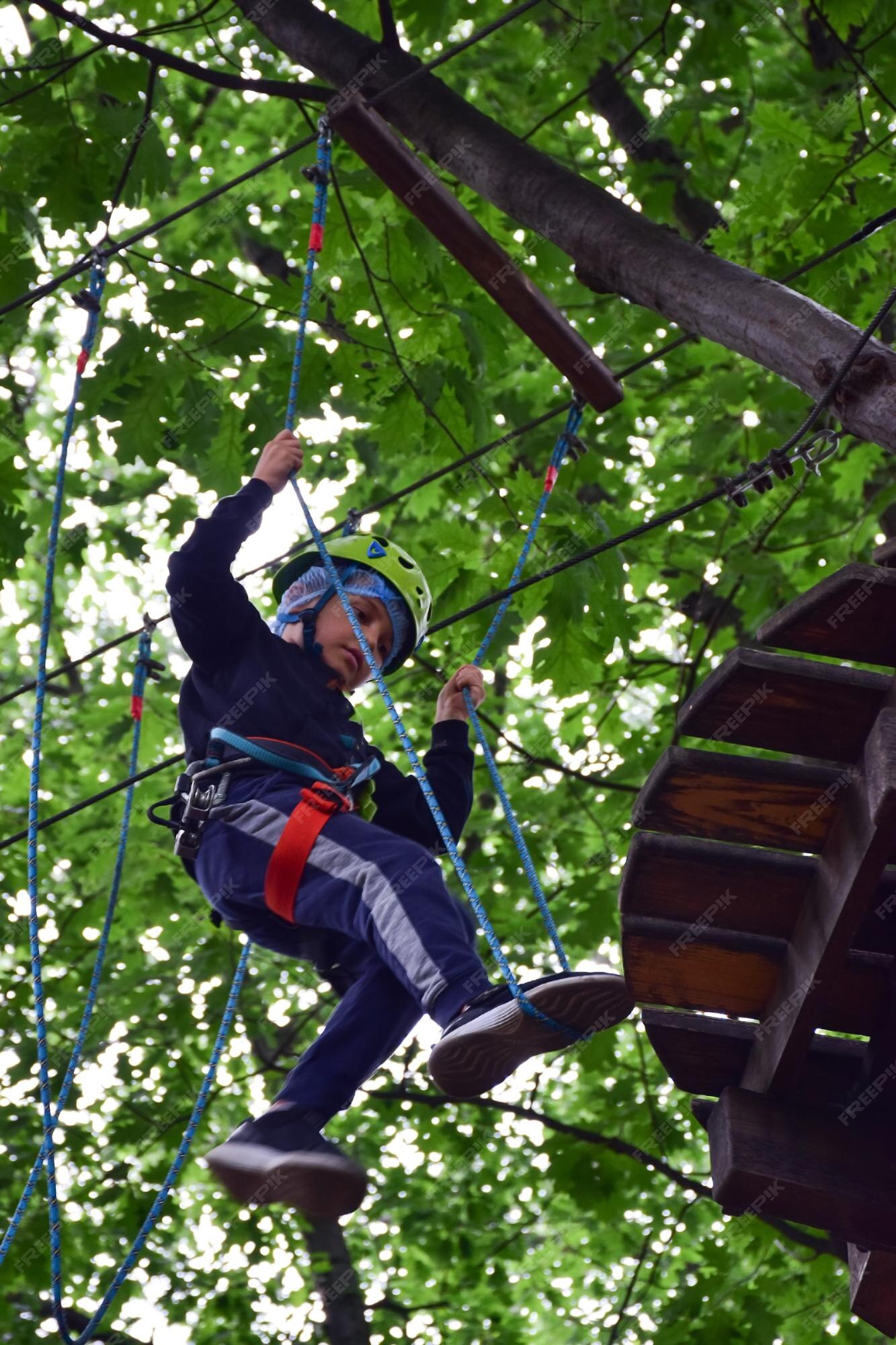 Plantando árboles Merecer chisme Un muchacho adolescente sube las escaleras colgantes de un árbol a otro en  un parque de atracciones de cuerda | Foto Premium