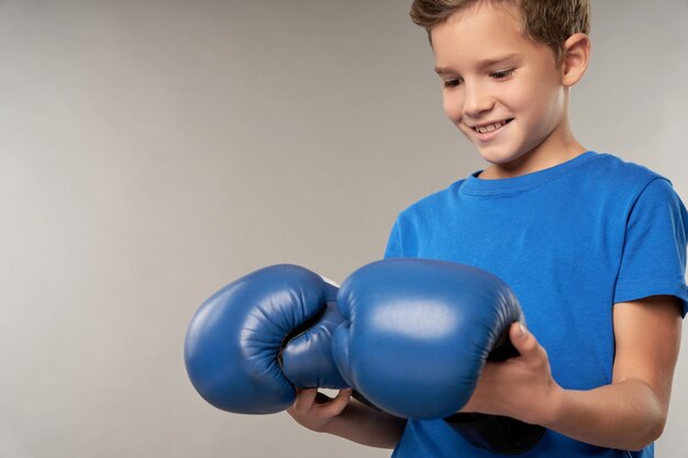 Muchacho alegre en camisa azul con guantes de boxeo