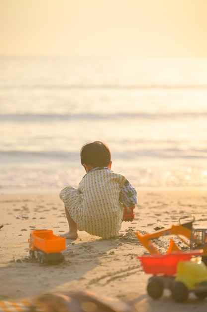 Muchacho asiático que juega en una playa arenosa cerca del mar