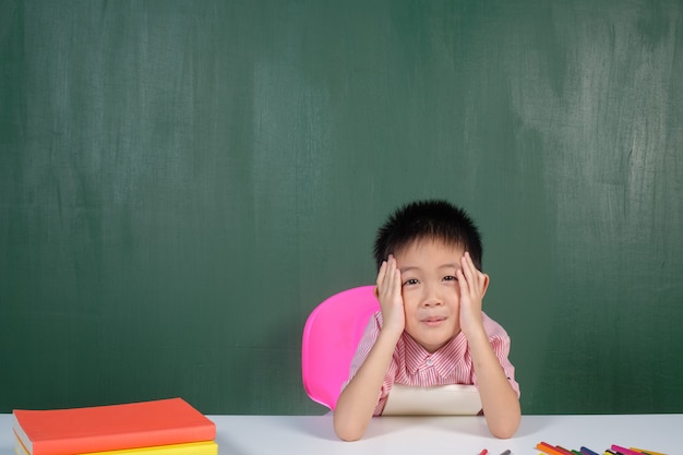 Muchacho asiático que mira en sala de juntas de tiza. La educación vuelve al concepto de la escuela