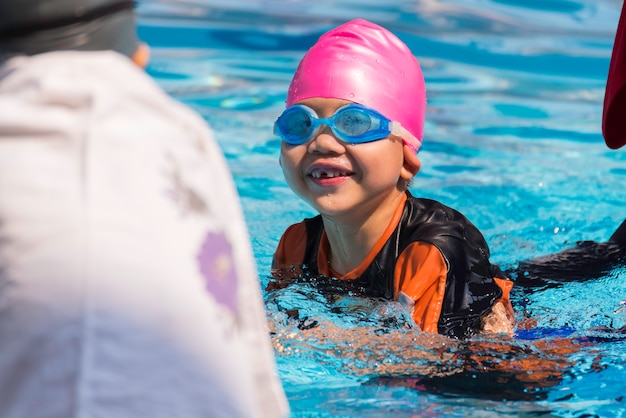 Muchacho asiático en el tiempo del día de la piscina