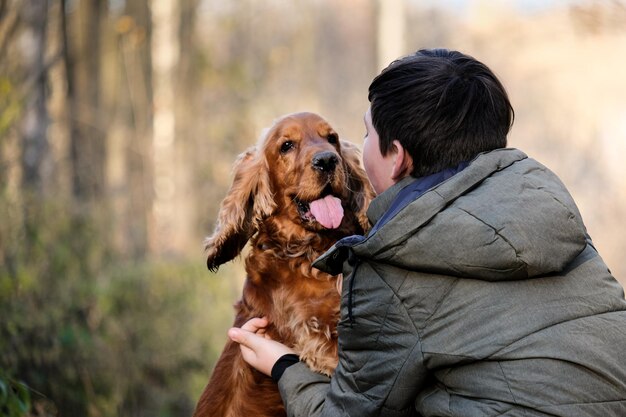 Muchacho caminando con cocker spaniel rojo en el parque