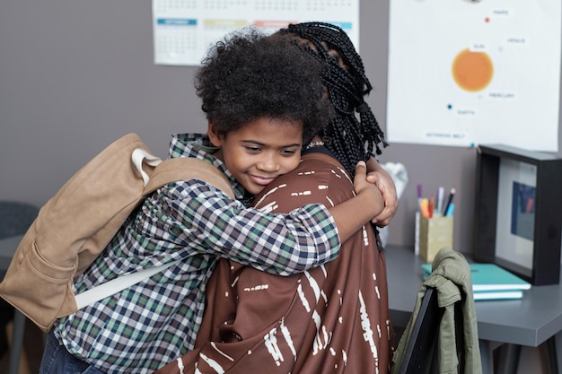 Muchacho cariñoso feliz que da el abrazo a su madre