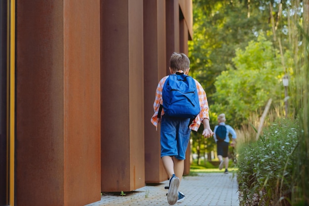 Muchacho caucásico caminando a la escuela usando mochila escolar Comienzo del año académico