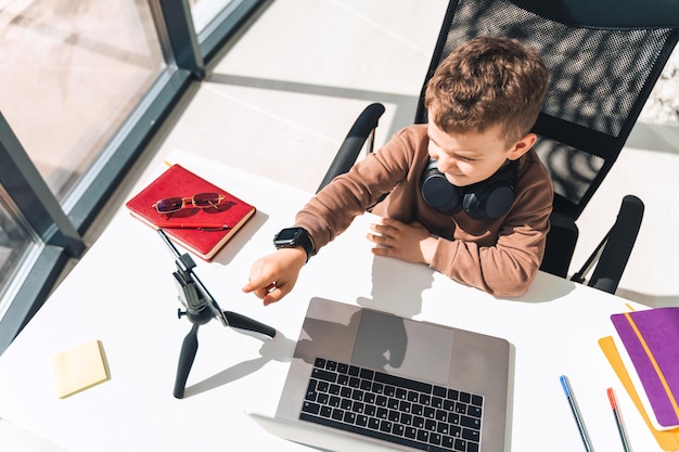 El muchacho está estudiando en línea en la computadora portátil