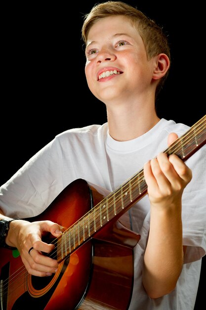 Muchacho feliz jugando en la guitarra acústica muchacho adolescente con guitarra clásica de madera