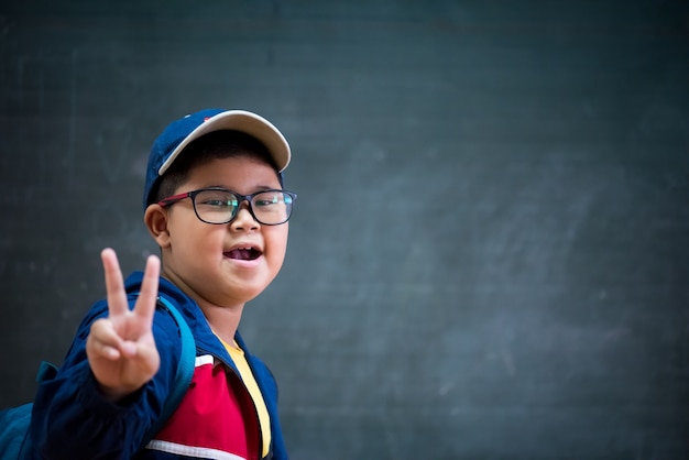 Foto muchacho feliz en los vidrios que muestran dos dedos para de nuevo al concepto de la escuela.