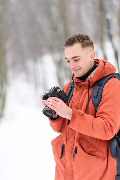 Muchacho de fotografía rubia mirando la foto de la cámara mientras camina en el bosque