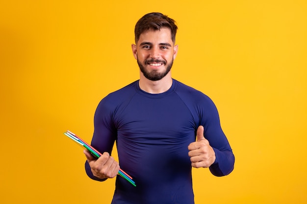 Foto muchacho joven estudiante sobre fondo amarillo. niño estudiante feliz