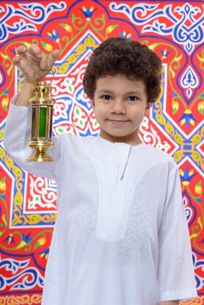 Muchacho joven sonriente con la linterna que celebra el Ramadán