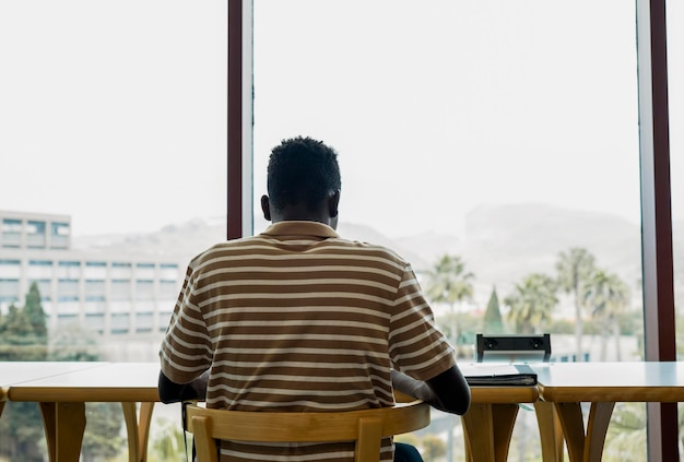 Muchacho negro joven que usa una tableta en una biblioteca