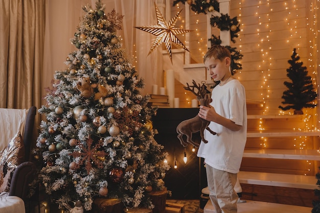 Muchacho del niño que adorna el árbol de Navidad en casa. Familia con niños celebran las vacaciones de invierno. Los niños decoran la sala de estar y la chimenea para Navidad.