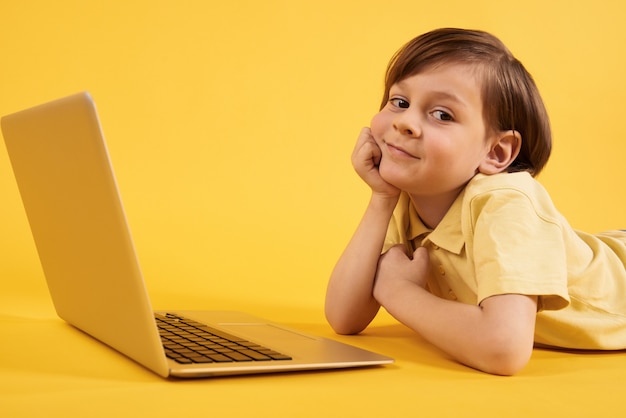 Foto el muchacho que sueña despierto con la computadora portátil miente en suelo.