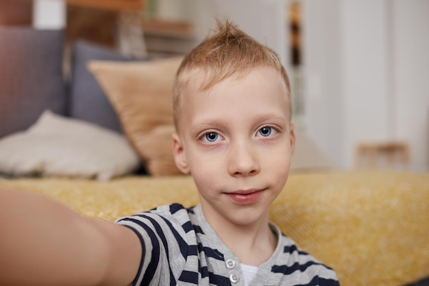 Muchacho rubio tomando selfie en casa