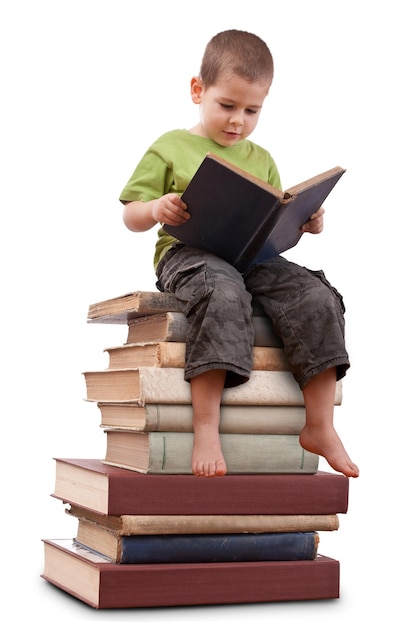 Foto muchacho sentado en una gran pila de libros