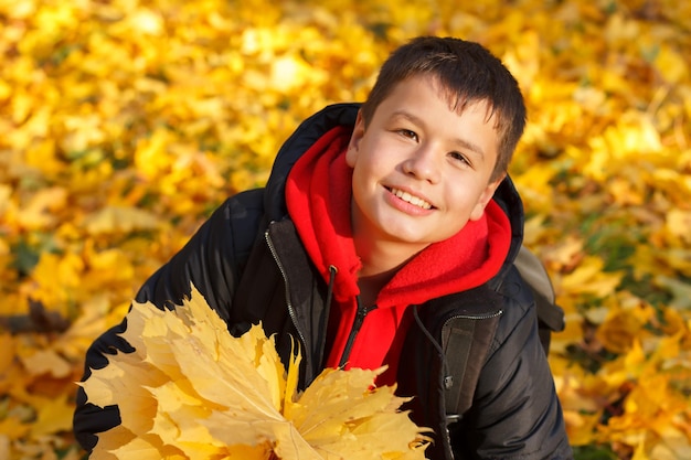 Muchacho sonriente feliz con hojas de otoño