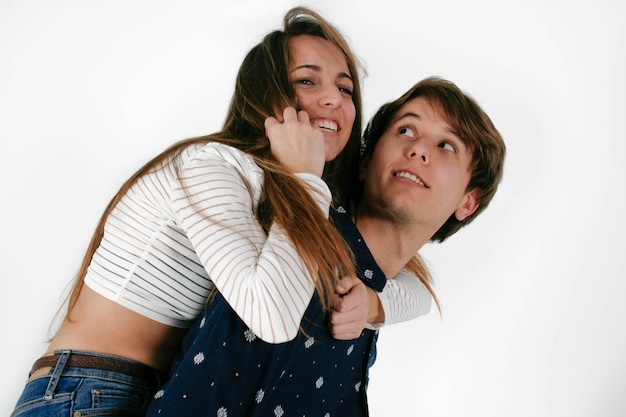 Muchacho sonriente joven que lleva a su novia en fondo blanco