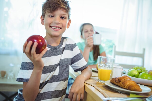 Muchacho sonriente que sostiene una manzana