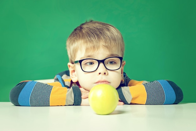 Muchacho triste con gafas y un primer plano de manzana